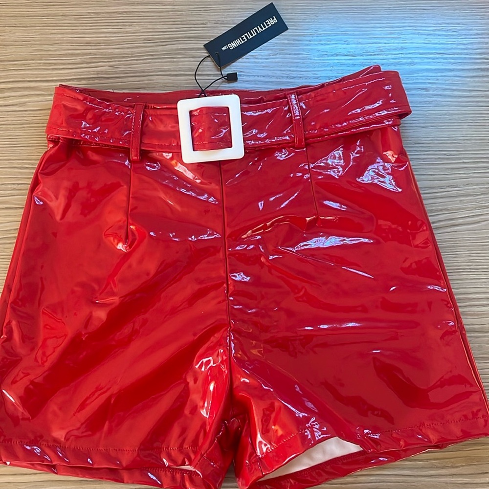 Pretty Little Thing Red vinyl shorts with a white belt buckle and hidden zipper